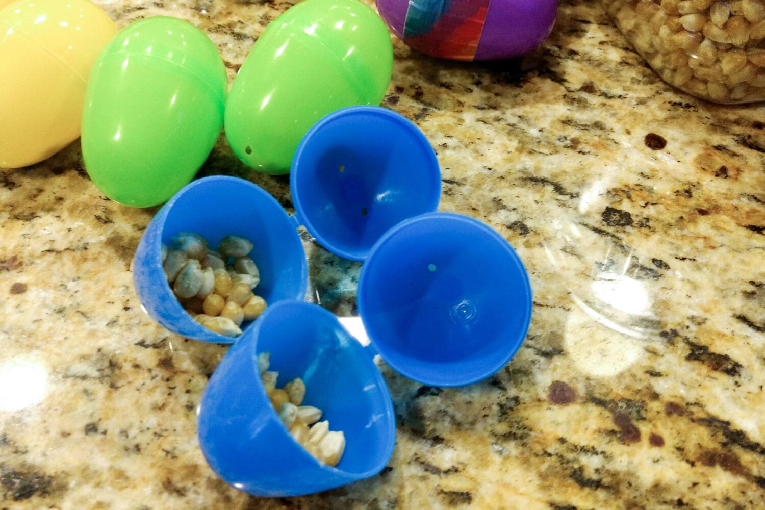 Filling homemade egg shakers with popcorn seeds in plastic Easter eggs